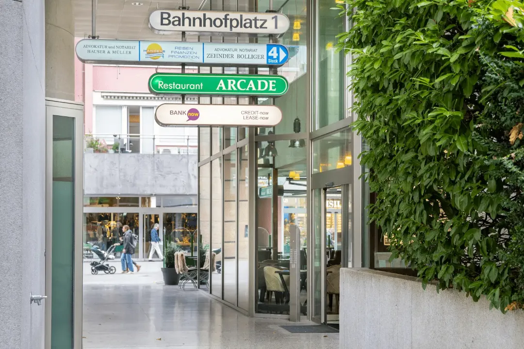Eingangsbereich zur BANK-now Filiale Baden mit Wegweisern bei Bahnhofplatz 1.