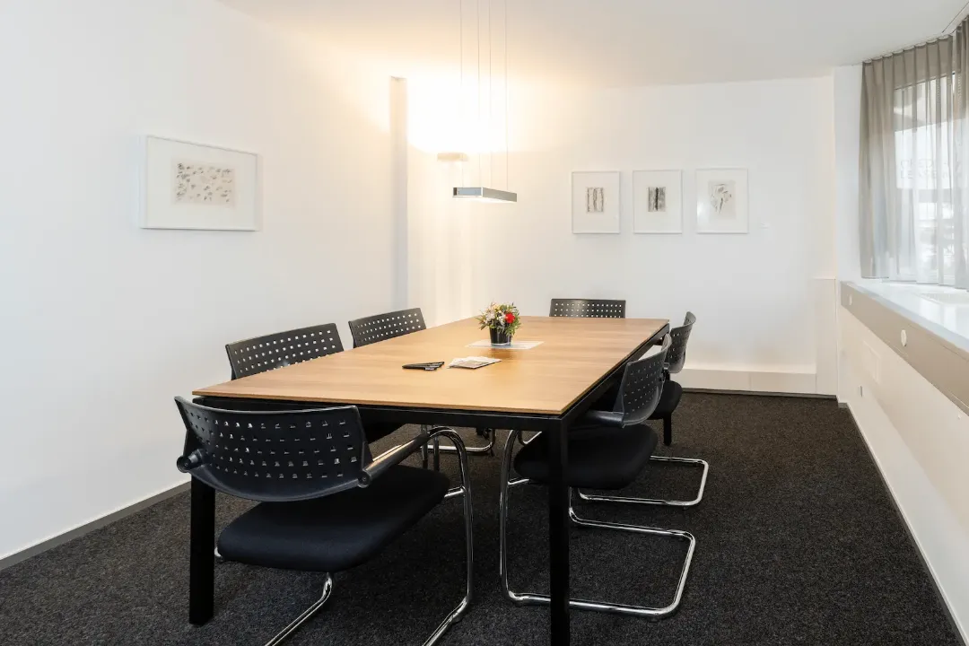 Zweiter Besprechungsraum der BANK-now Filiale Chur mit Tisch, Stühlen und heller Fensterfront.