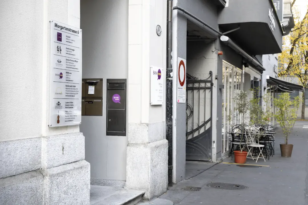 Zweite Aussenansicht der BANK-now Filiale Luzern mit Eingang, Briefkästen und Hinweisschildern.