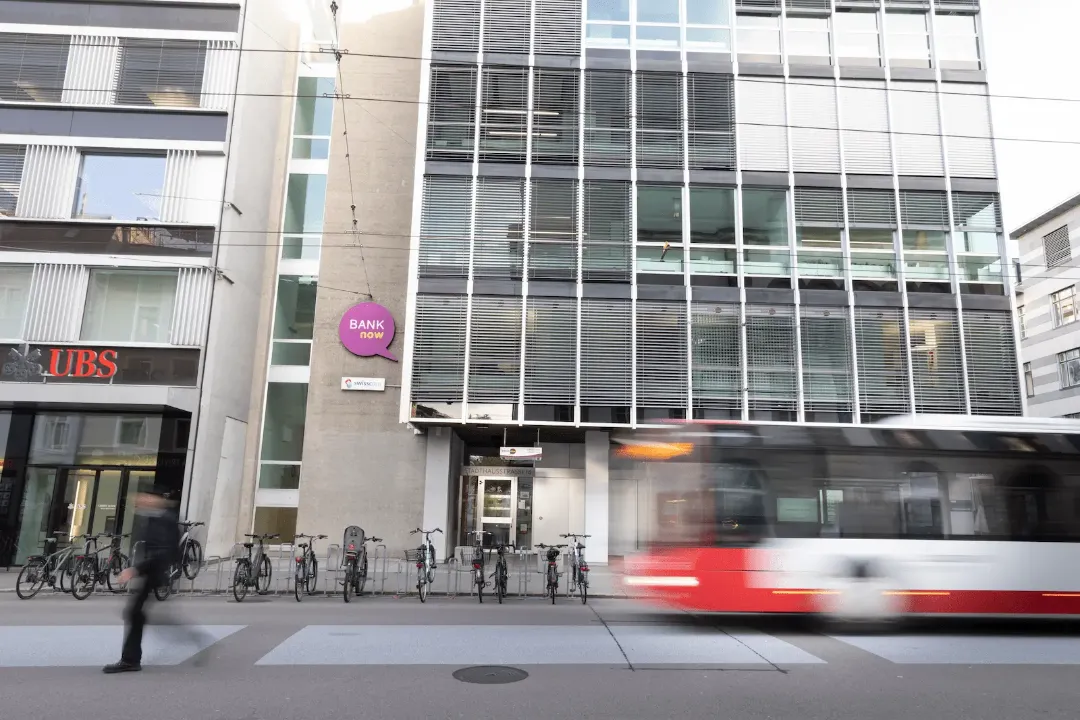 Aussenansicht der BANK-now Filiale Winterthur mit Eingang und vorbeifahrendem Tram.