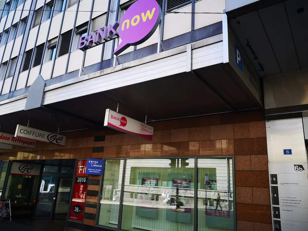 Eingang der BANK-now Filiale in Fribourg mit BANK-now Logo über dem Eingang