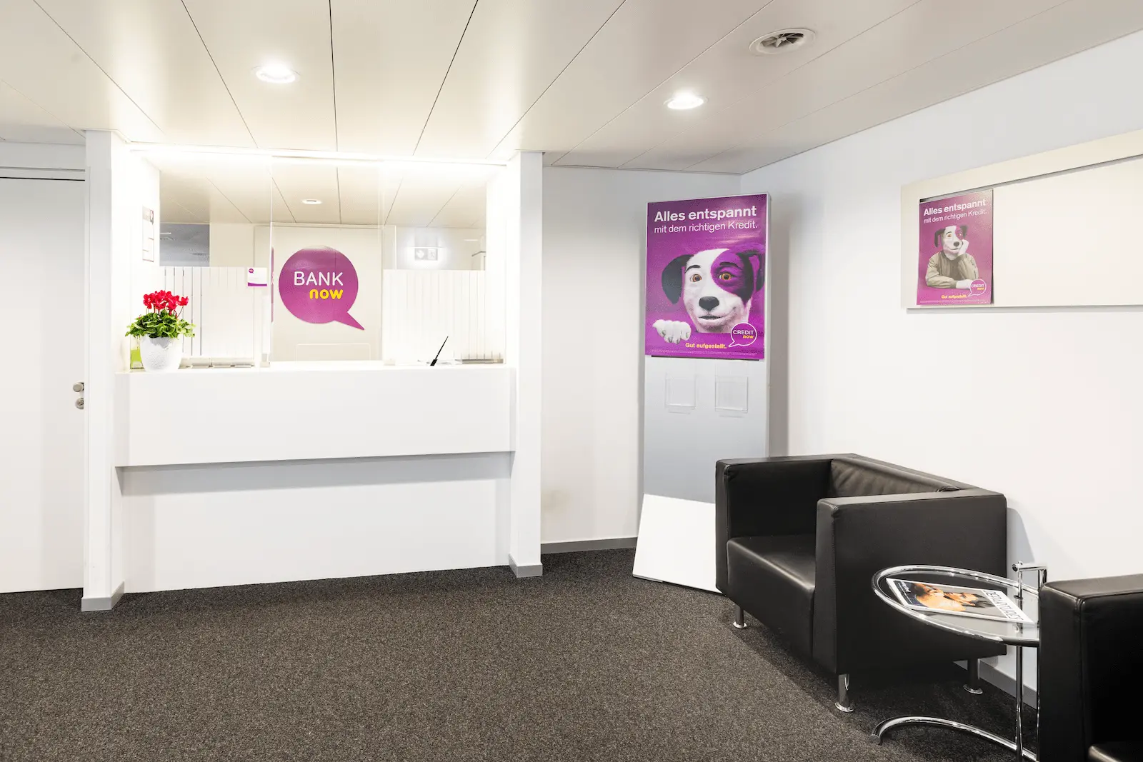 Wartebereich der BANK-now Filiale Basel mit Sitzgelegenheiten und Postern.