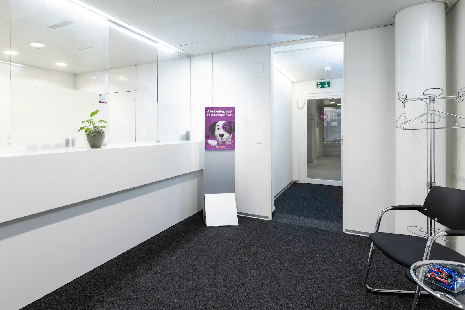 Heller Schalterbereich der BANK-now Filiale Baden mit Empfangstheke und Sitzgelegenheit.
