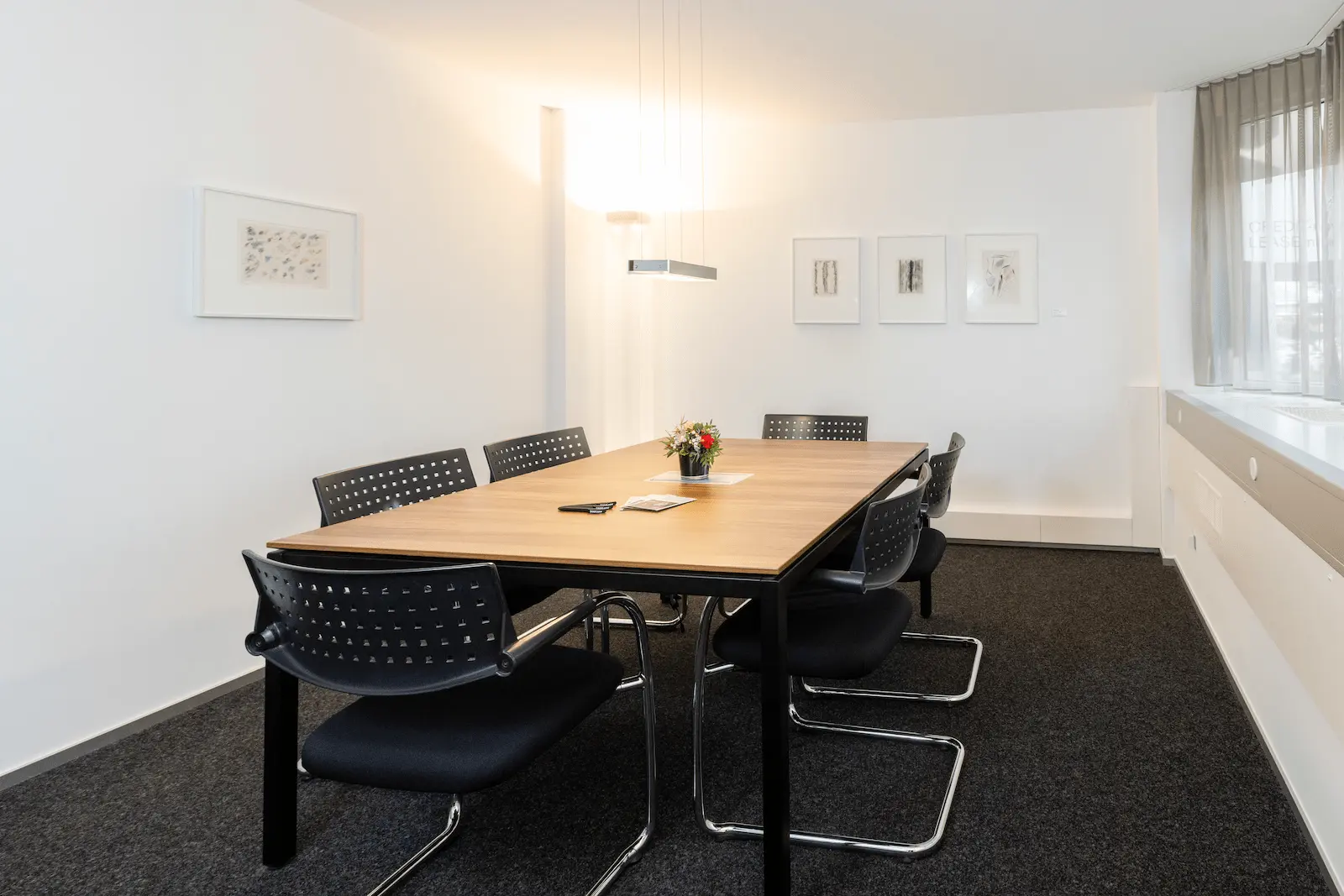 Zweiter Besprechungsraum der BANK-now Filiale Chur mit Tisch, Stühlen und heller Fensterfront.