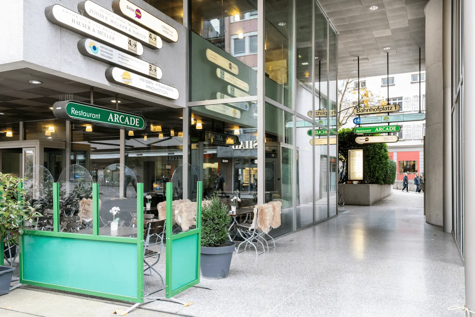 Zweiter Blick auf den Durchgang zum Eingang der BANK-now Filiale Baden mit Schildern.